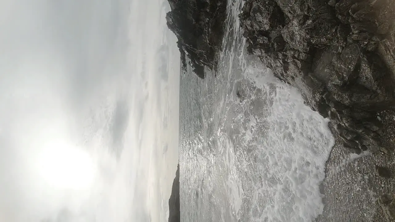 VERTICAL slow motion ocean waves crashing against Anglesey rock coastline at sunrise