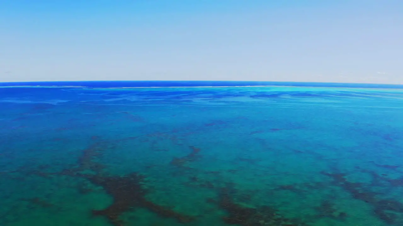 fly over with a drone above a beautiful gigantic blue lagoon during a beautiful day with no cloud in the sky