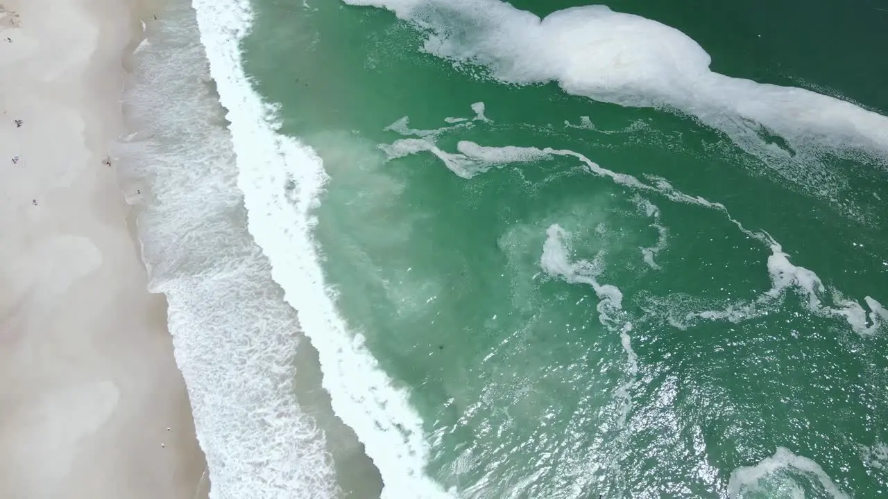 White foam floating in clan green water ocean and brown sandy coast