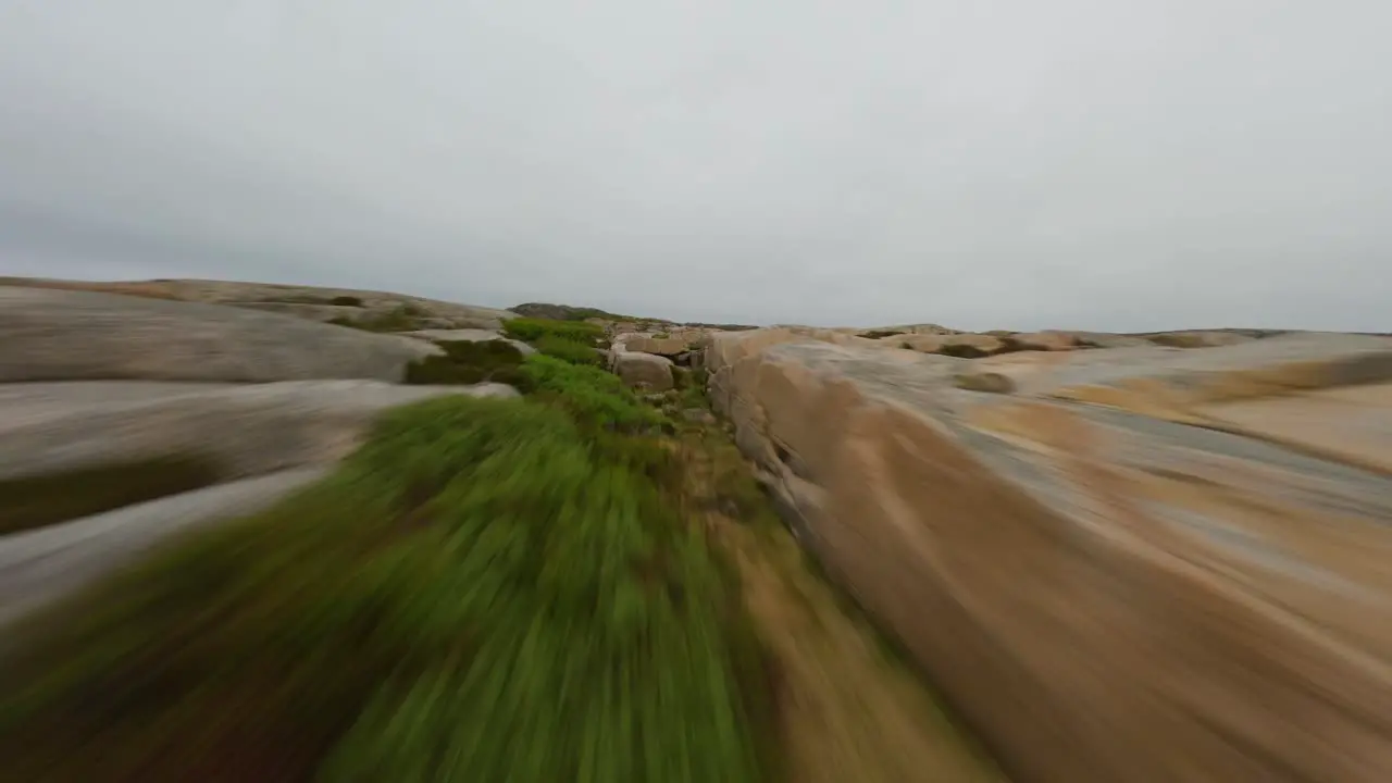 FPV drone flying fast and low over a rocky terrain of Ramsvik shoreline in Sweden