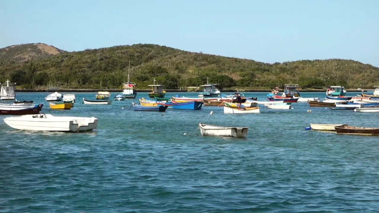 man rows on a raft between wooden boats in a calm tropical bay