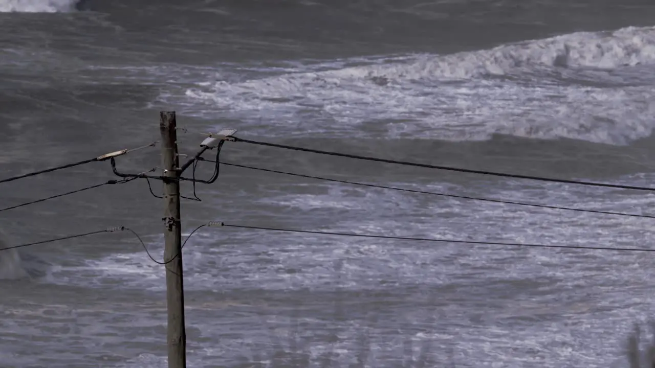 View from the hill down to the stormy ocean and the power line mast