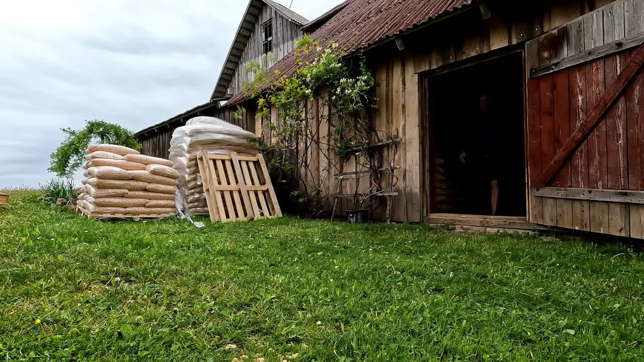 Man taking bags of material into wooden farm building time lapse