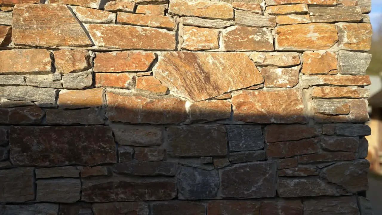 Sunset golden hour light hitting the side of a rustic stone walled building casting harsh shadows with luxury feel