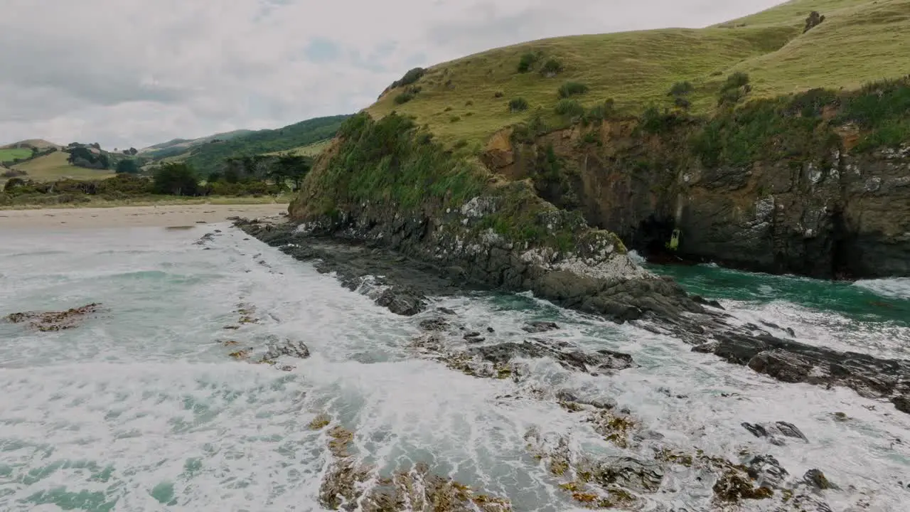 Aerial reversing over rough and wild cliff coastline with white wash waves breaking against rocks in Cannibal Bay in the Catlins South Island of New Zealand Aotearoa