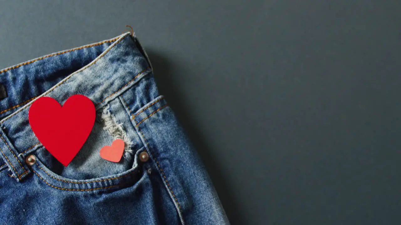 Close up of jeans with red hearts on grey background with copy space