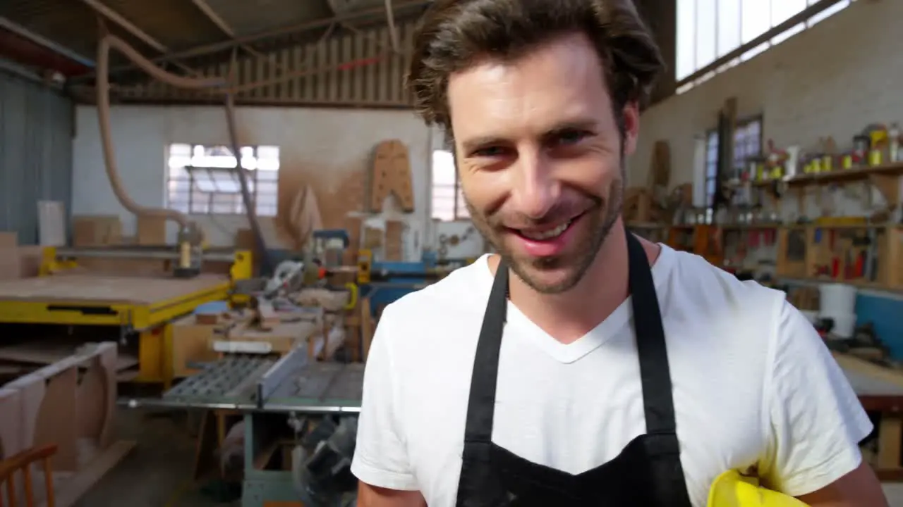 Attractive carpenter using his phone and smiling for camera