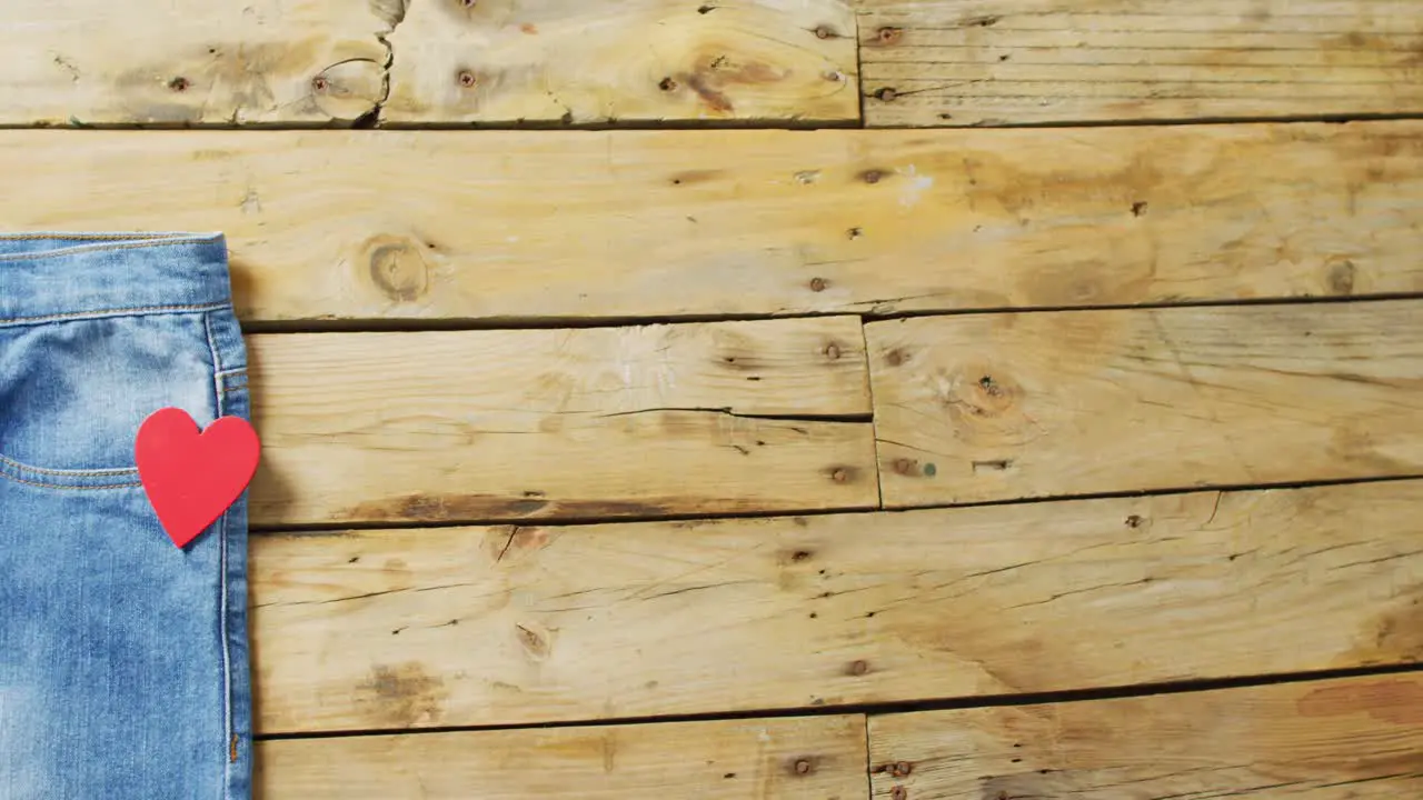 Close up of jeans with red heart on wooden background with copy space