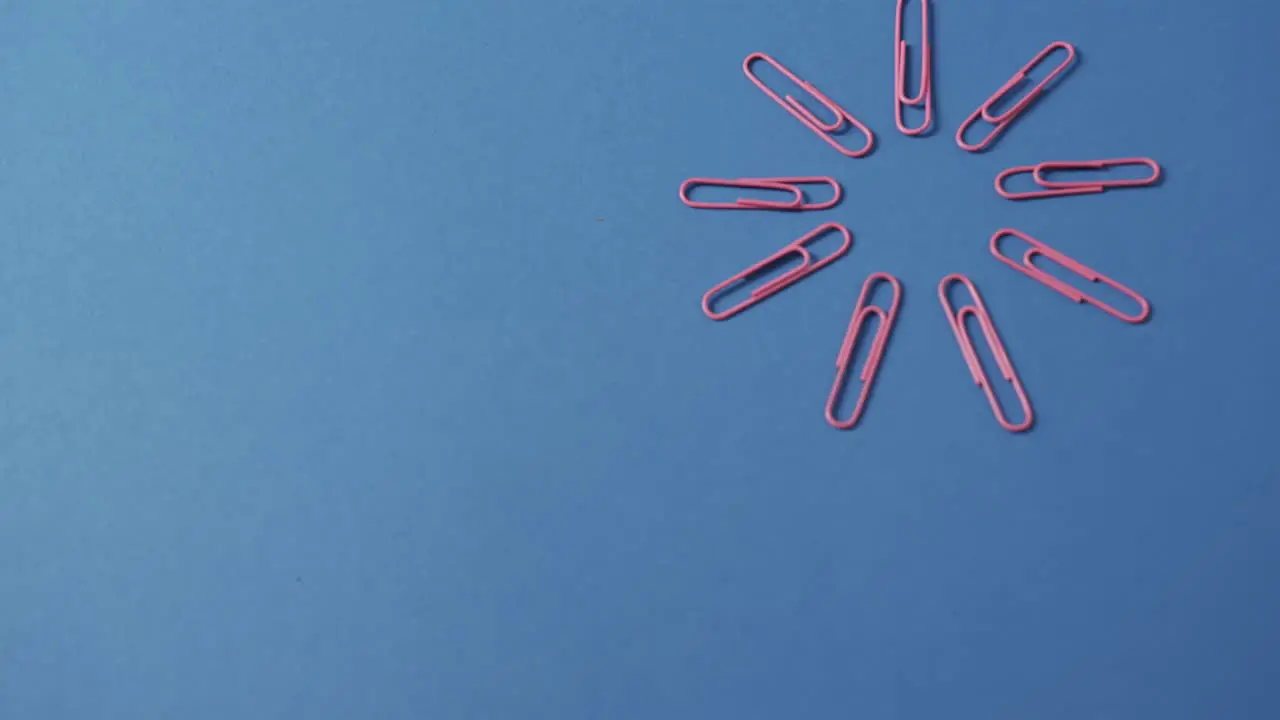 Close up of pink paper clips in circle and copy space on blue background