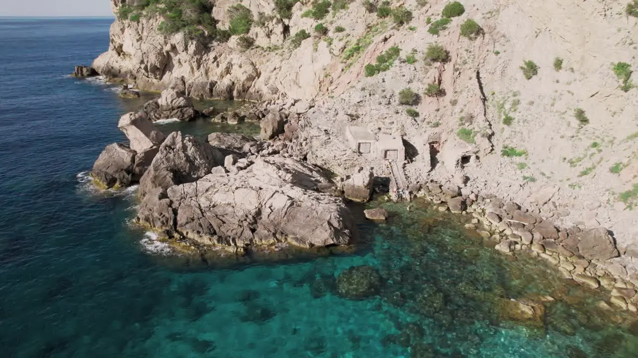 Close up rocks in ocean at bottom of tall cliff on coast of island