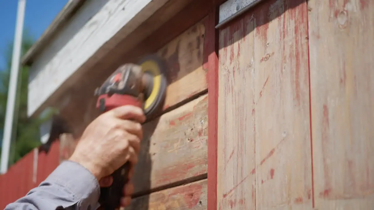 Removing old paint from wooden house by sanding machine