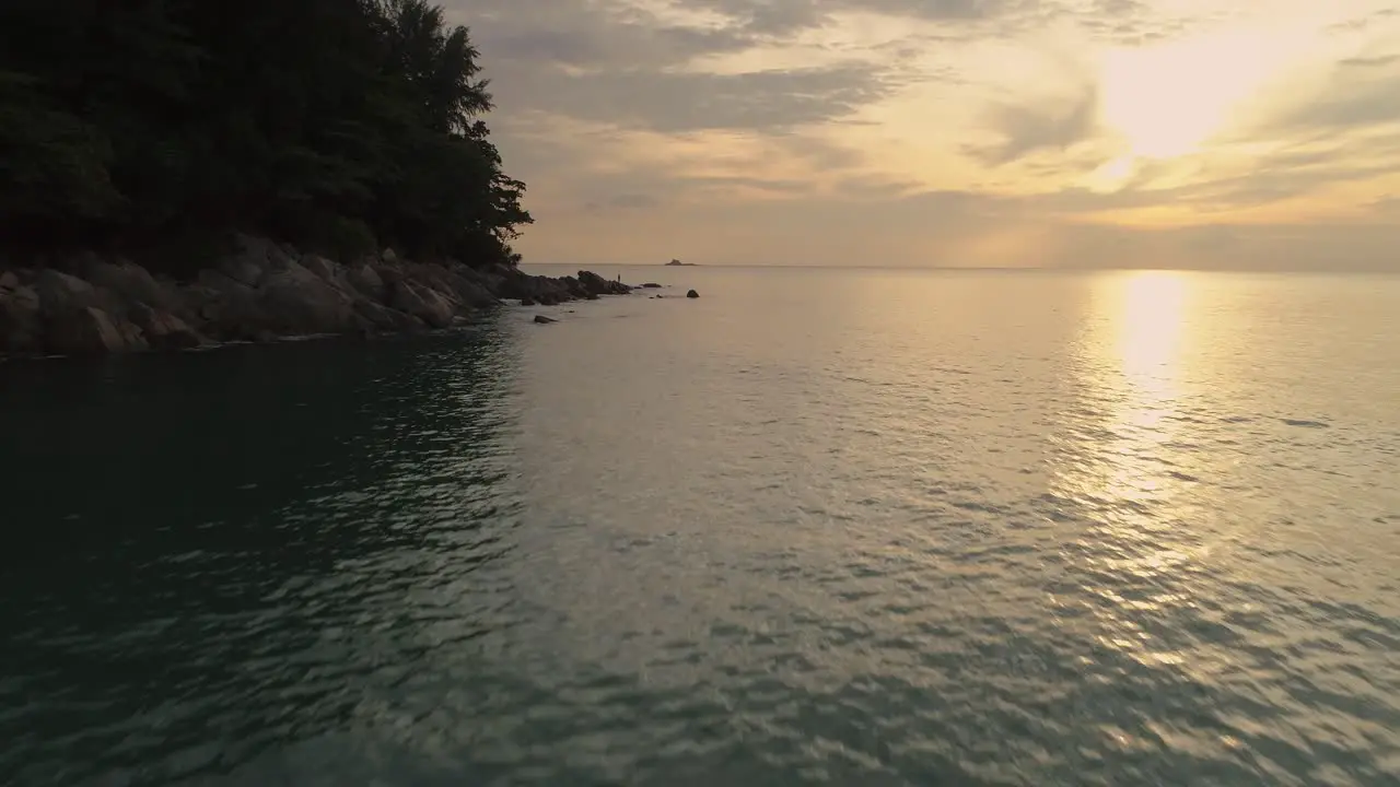 Bright golden sunset at Nai Thon Beach with tropical cliffs aerial