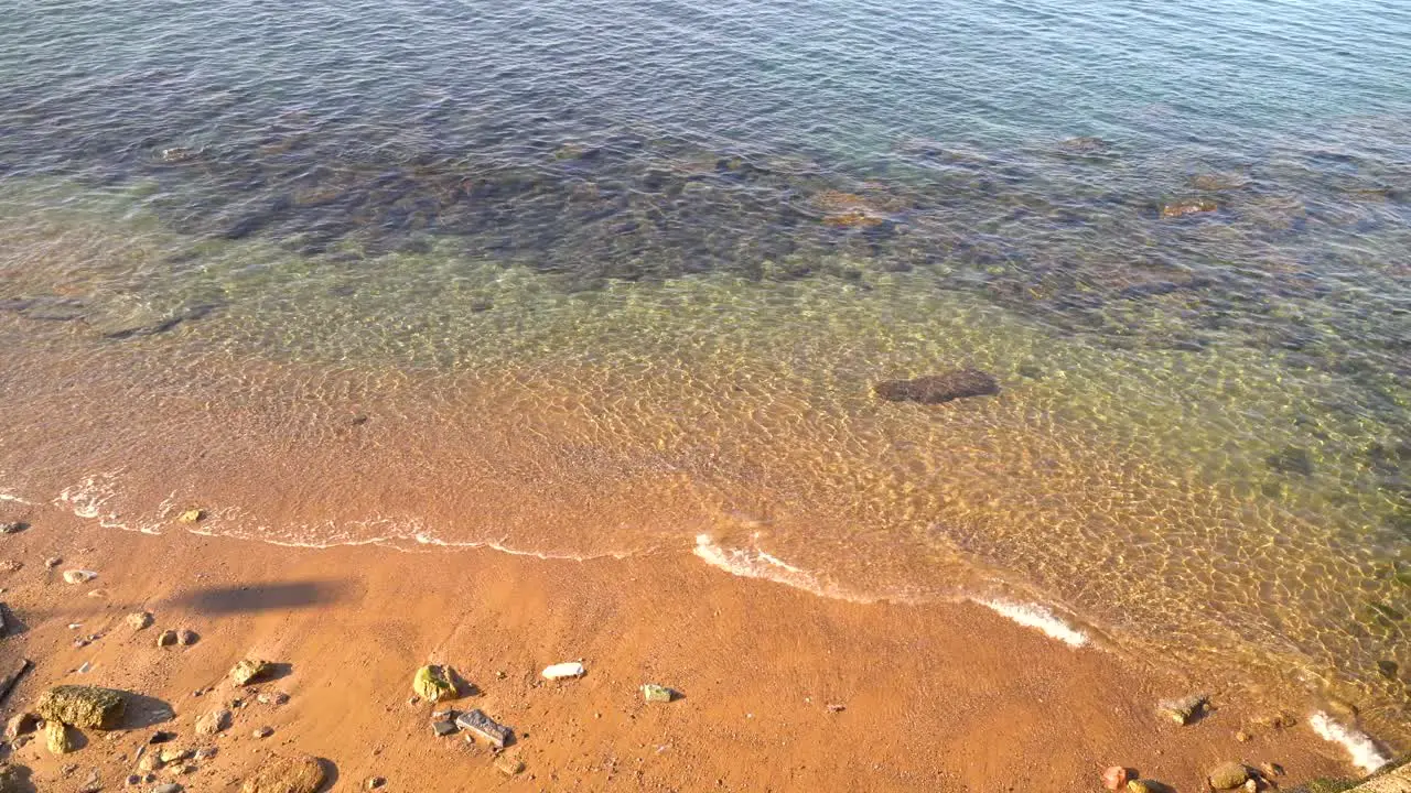 Locked off shot looking down at yellow sand and ocean