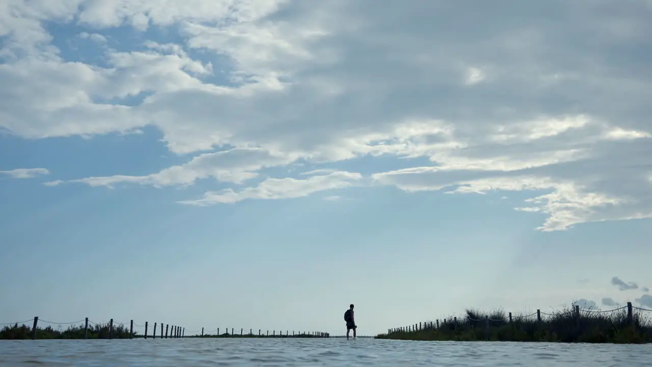 Wide Shot Of Male Walking In Flooded Beach Area