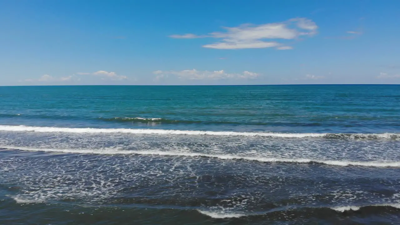 Turquoise sea water and white waves foaming on shore of Adriatic sea on a summer day with bright blue sky