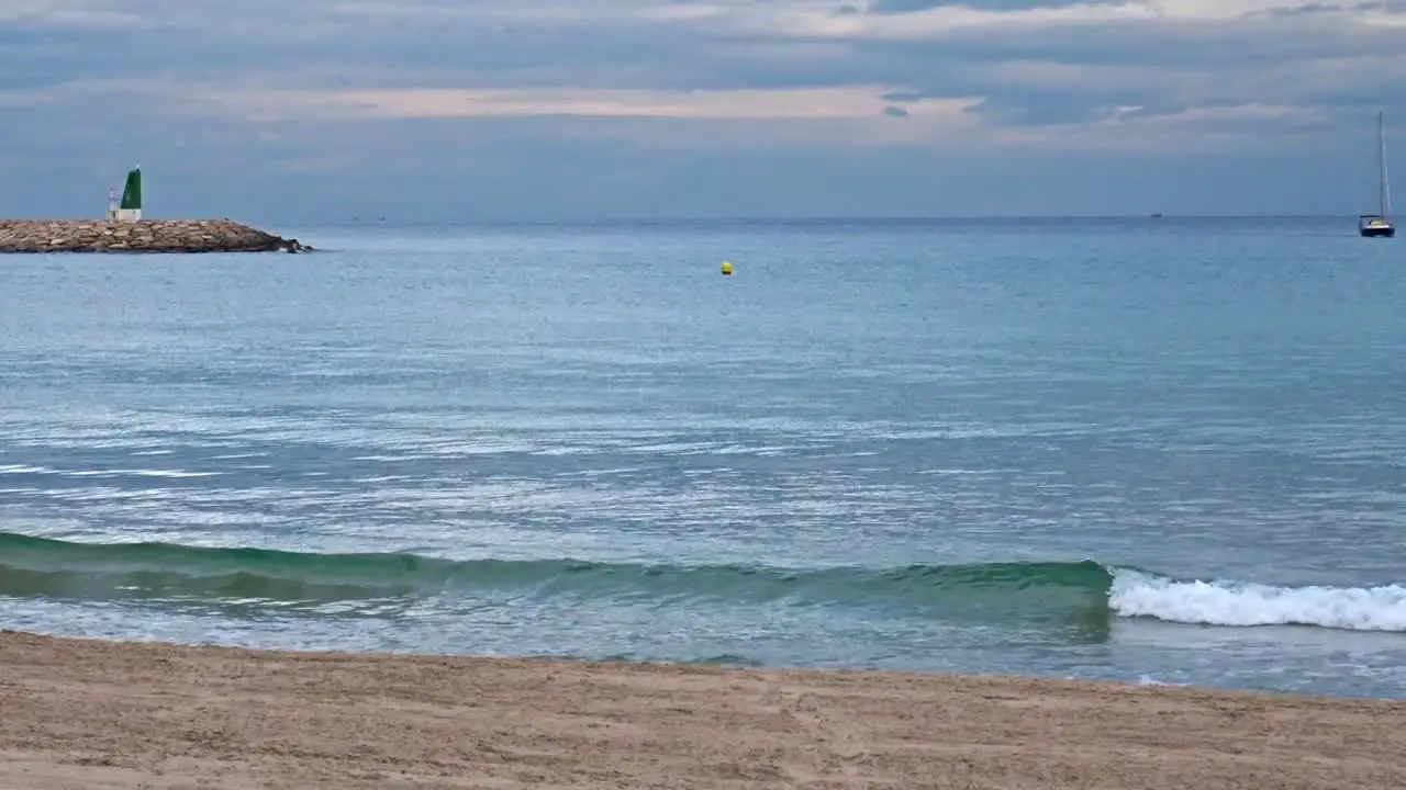 A sailboat on the horizon in the port of El Campello Spain on a cloudy day