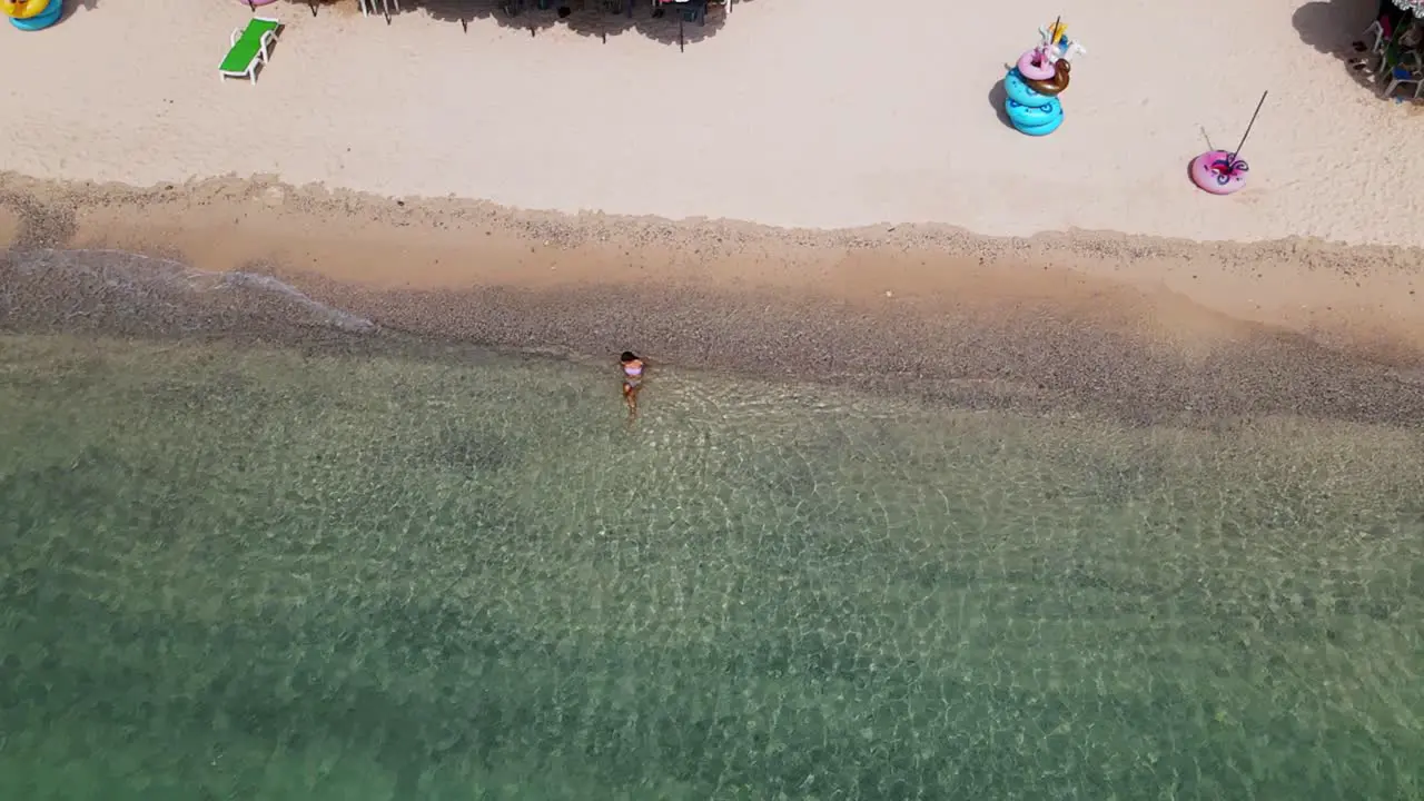 4k aerial drone footage of a lone beach babe relaxing in the beautiful coastal waves of a deserted resort in Ko Larn Island Thailand