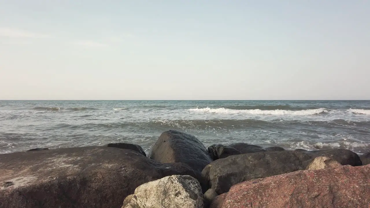 Pedestal up shot rising from behind rocks to reveal wide view of sea