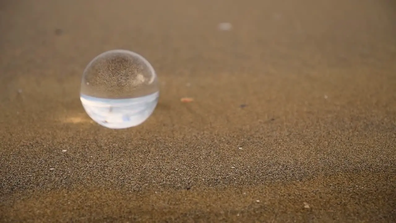 crystal ball reflecting upside down with zooming looking effect on a beach on a cloudy and windy day of winter