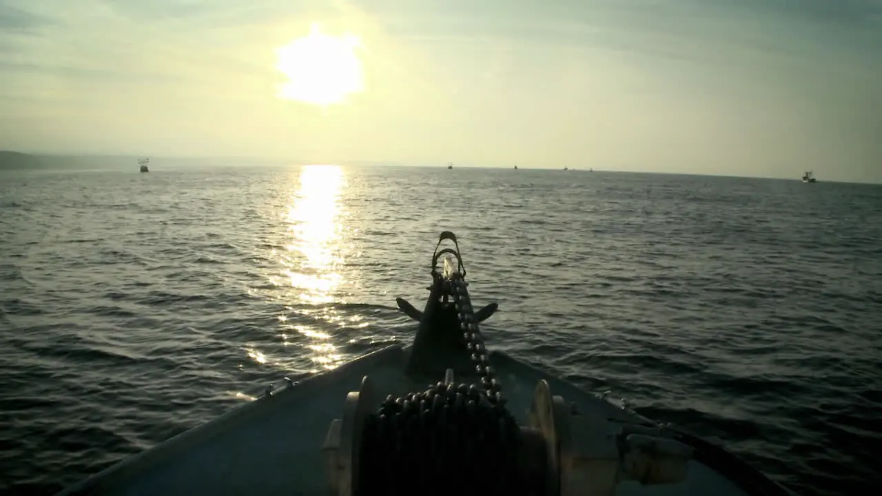 A boat moves through the water as the sun sets