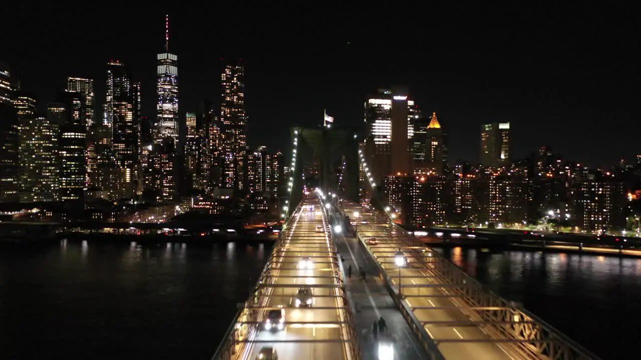 A slow low drone shot of the NYC skyline from the Brooklyn Bridge at night