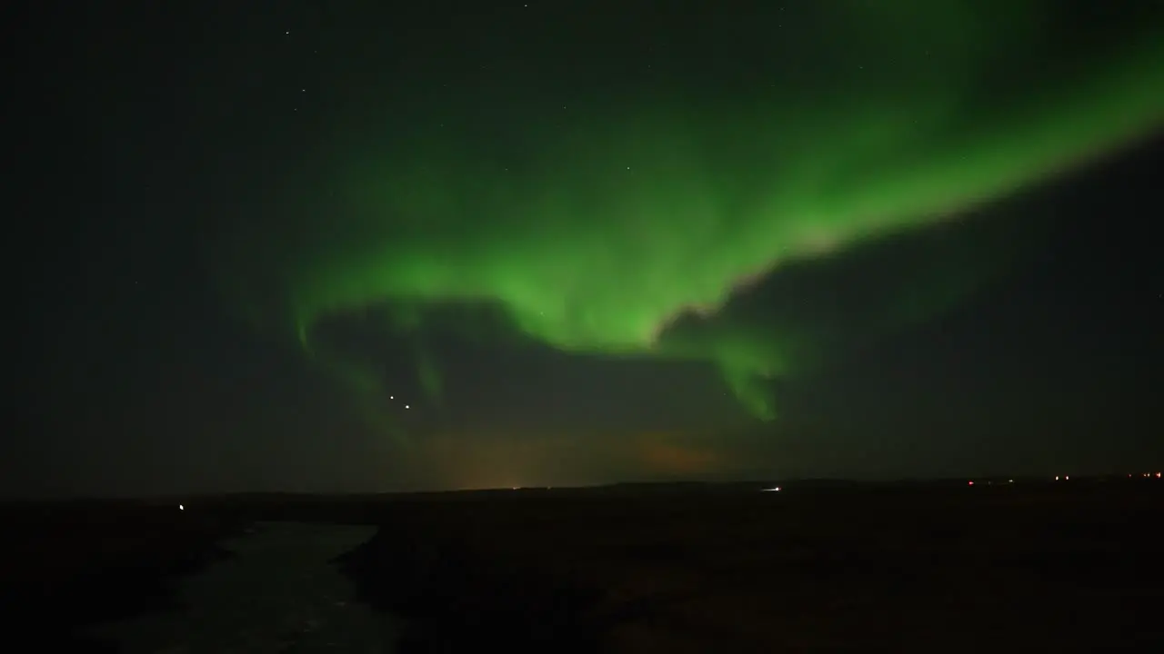 Panorama shot of green colored Northern Lights in motion against dark sky above Iceland Island