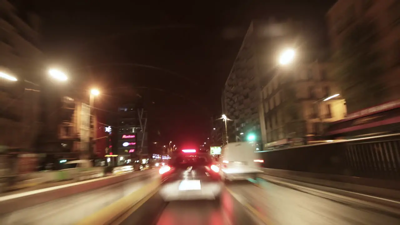 Timelapse captures the frenetic pace of a night-time street scene dominated by streaks of light from passing cars under the glow of street lamps