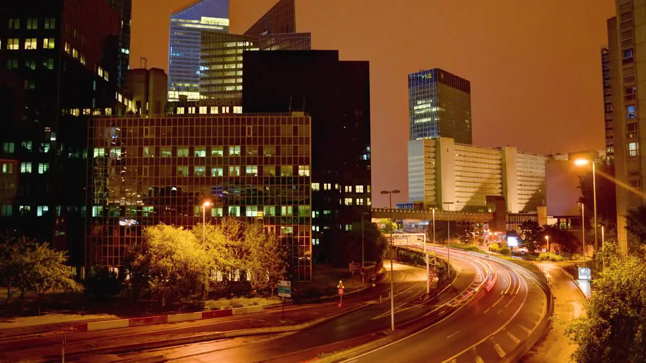 From a high vantage point a timelapse captures the busy bustling essence of a city at night with a highway threading its way through lit-up modern skyscrapers