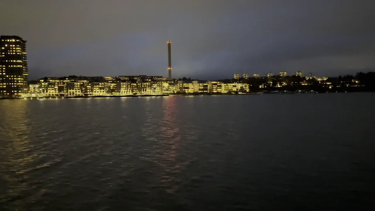 Traveling by boat during night time approaching the harbour of a smaller city on the starboard side