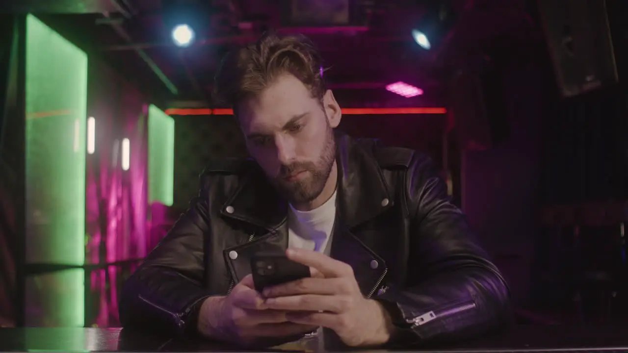 Serious Bearded Man Using Mobile Phone While Sitting At Bar Counter