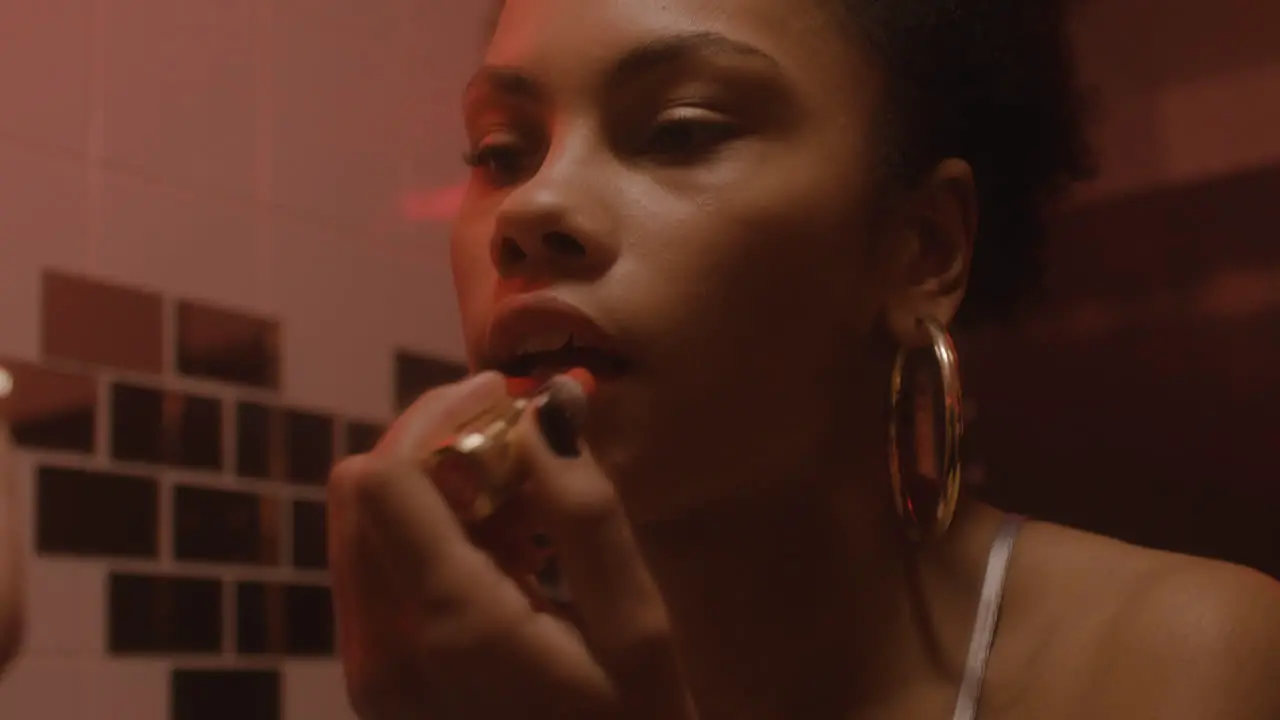 Close Up Of A Beautiful Girl Putting Lipstick On While Looking At Mirror In A Bar Bathroom 1