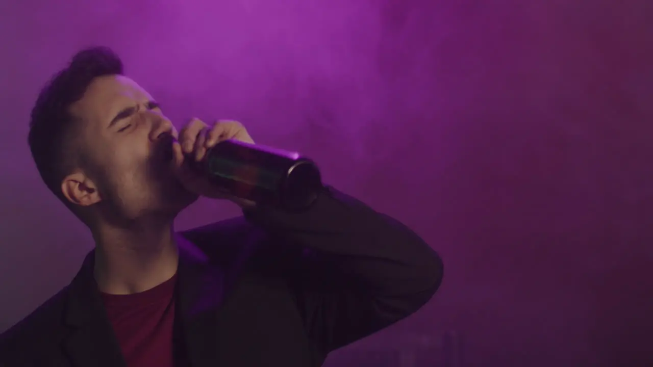 Young Man Drinking Beer And Dancing At Disco