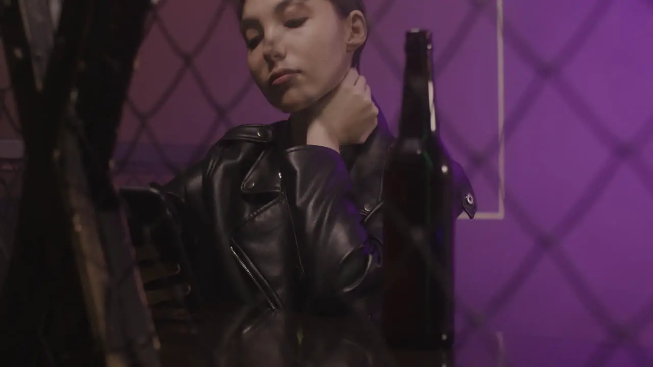 Serious Girl In Leather Jacket Drinking Beer And Using Mobile Phone While Sitting On A Stool At Disco 1