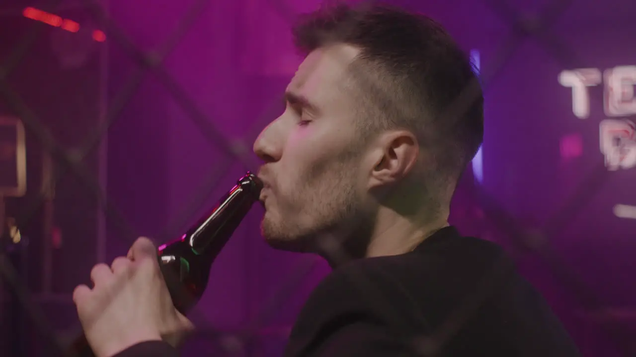 Young Man Drinking Beer While Sitting Alone At Disco Club