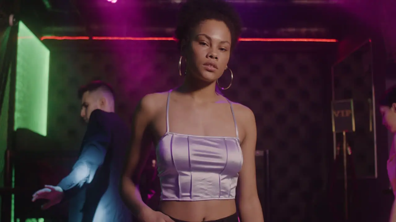 Portrait Of Beautiful Girl Looking Confident At Camera At Disco While Her Friends Dancing Behind Her 4