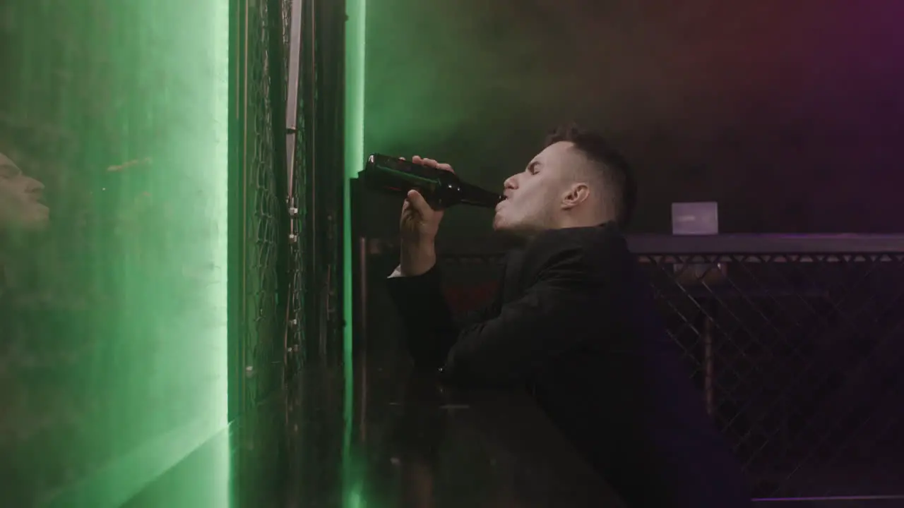 Young Man Drinking Beer While Sitting Alone At Disco Club 1