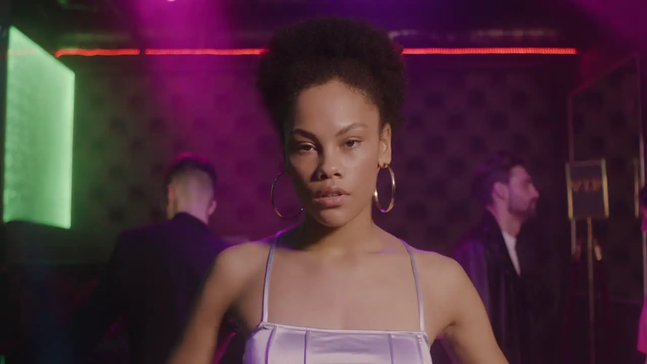 Portrait Of Beautiful Girl Looking Confident At Camera At Disco While Her Friends Dancing Behind Her 2