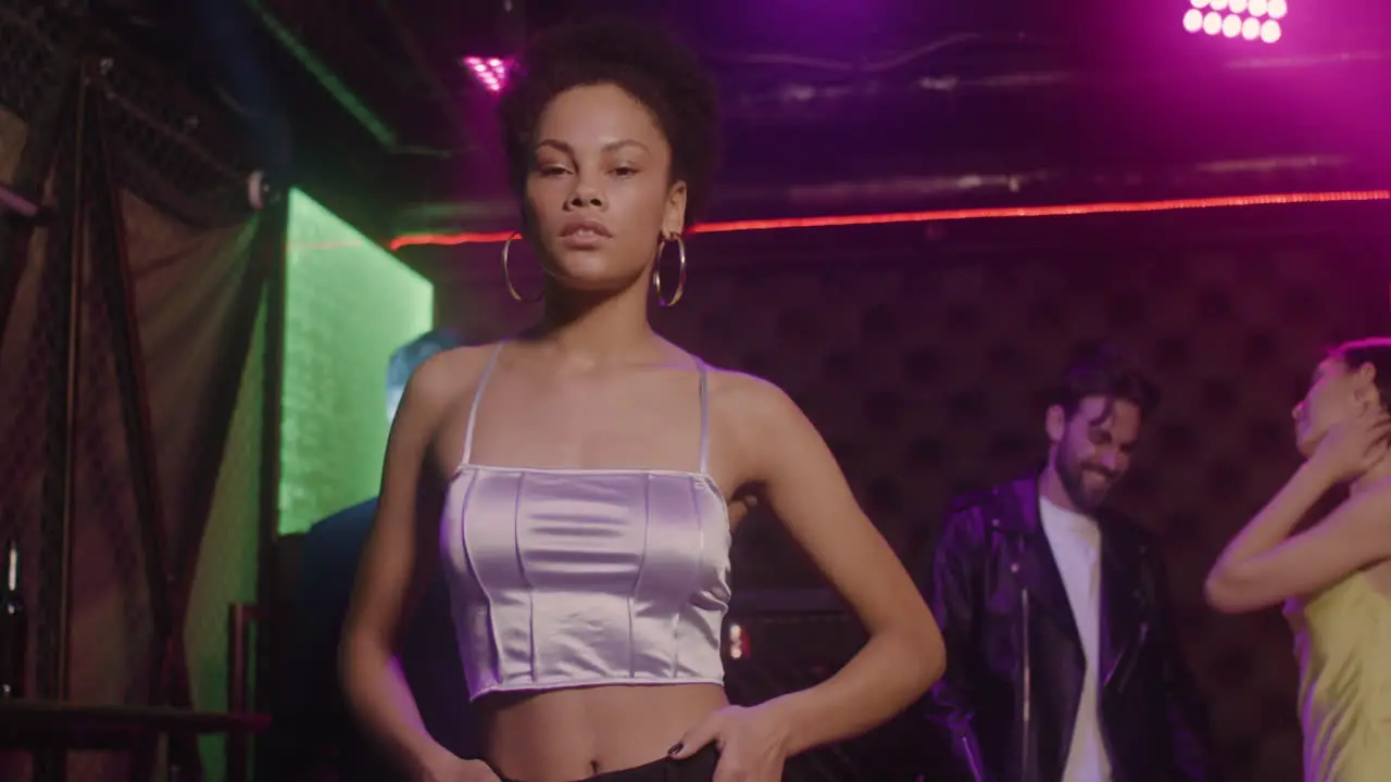 Portrait Of Beautiful Girl Looking Confident At Camera At Disco While Her Friends Dancing Behind Her 5