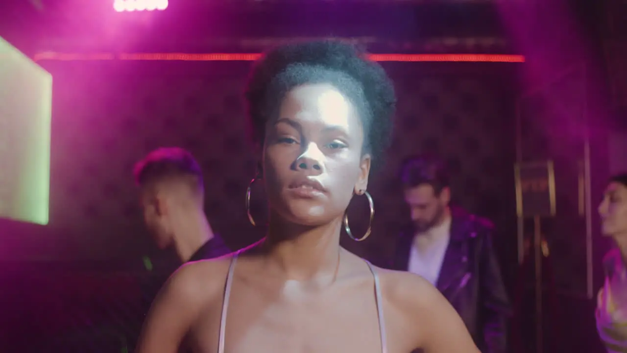 Portrait Of Beautiful Girl Looking Confident At Camera At Disco While Her Friends Dancing Behind Her