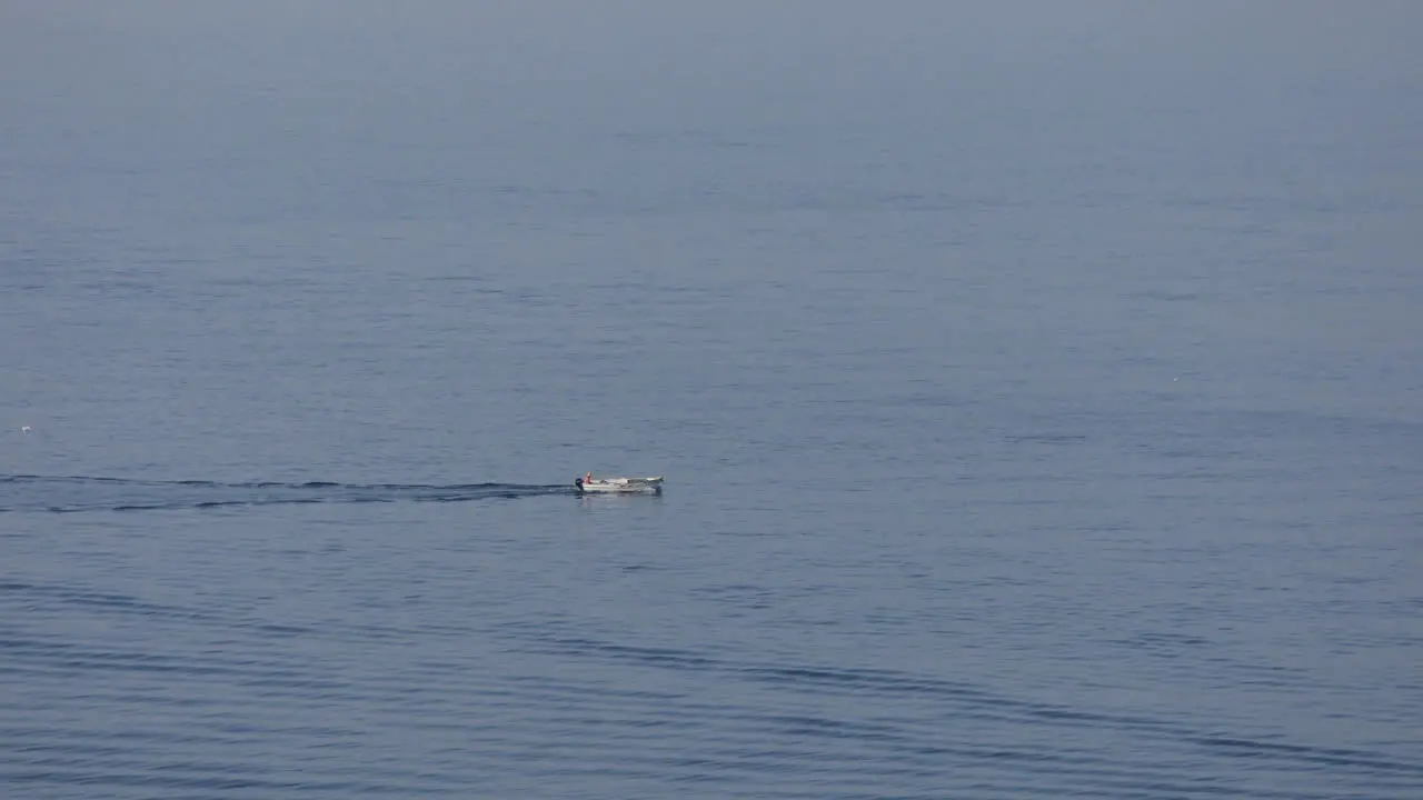 Motorboat sailing on calm sea surface tracing seawater at summer morning