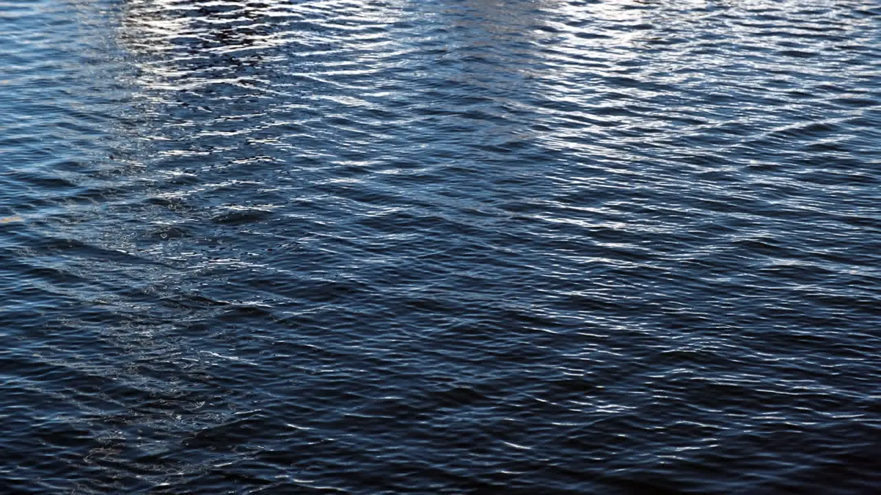 Patterns of blue ocean waters moving with reflection of a boat seen in Santa Monica