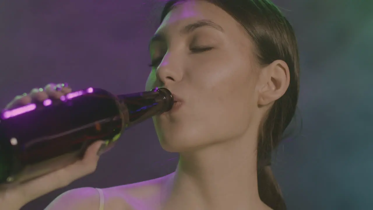 Close Up Of A Beautiful Girl With Closed Eyes Drinking Beer And Dancing At Disco