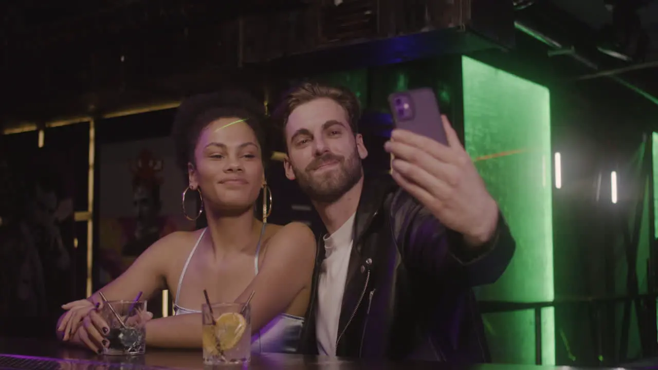 Multiethnic Couple Taking A Selfie Photo While Sitting At Bar Counter