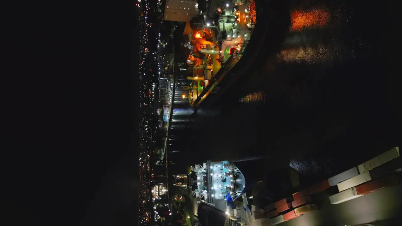 Vertical Shot Of An Industrial Port With Cargo Vessels And Containers At Night