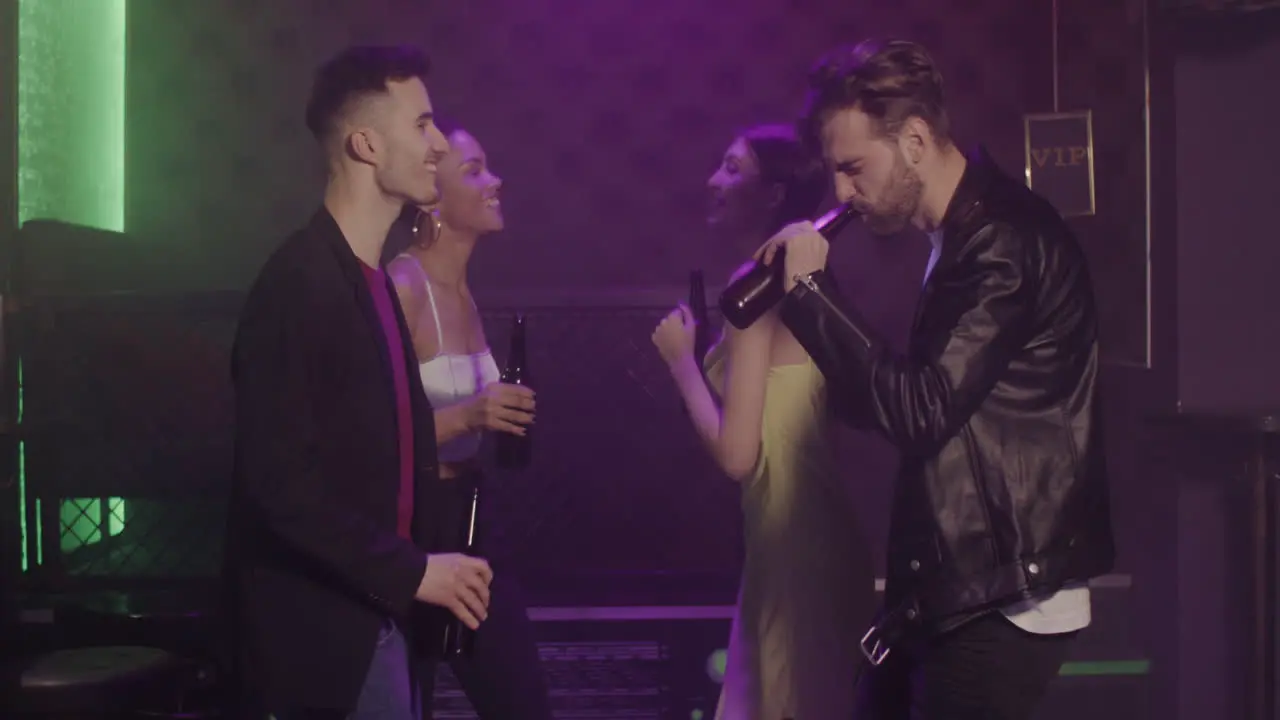 Group Of Four Young Friends Drinking Beer And Dancing At Disco 1