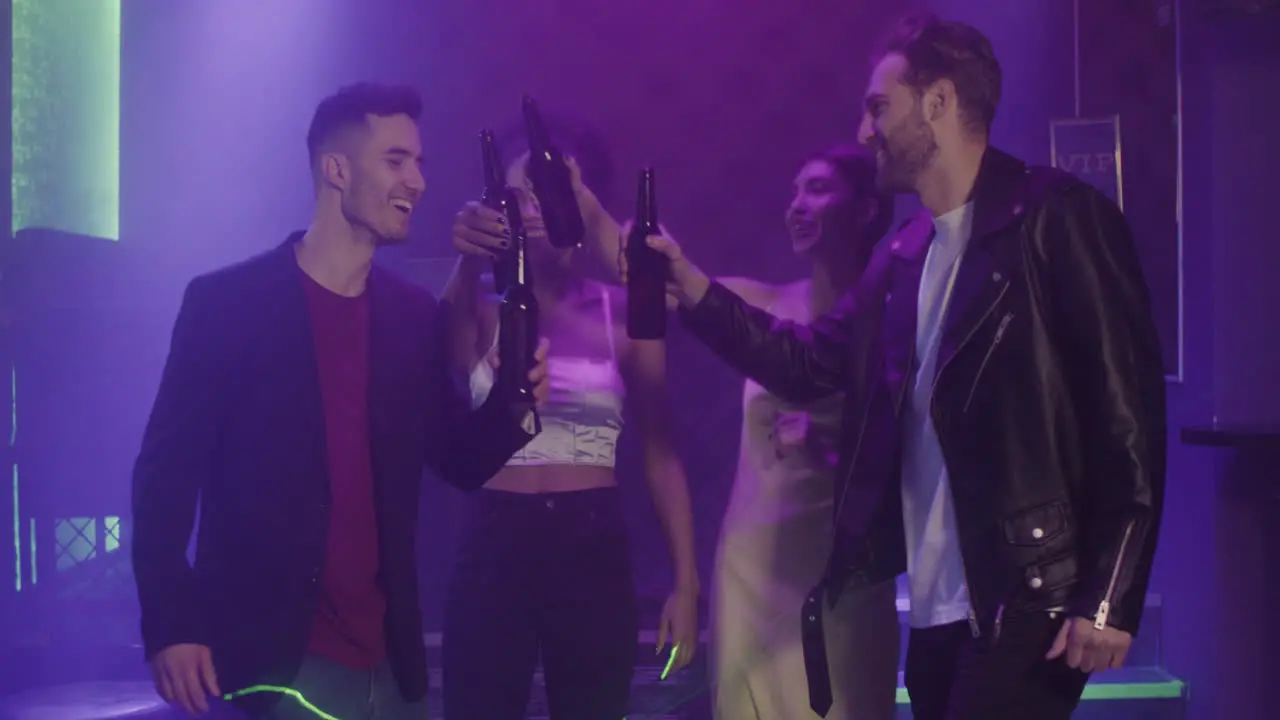 Group Of Four Young Friends Drinking Beer And Dancing At Disco