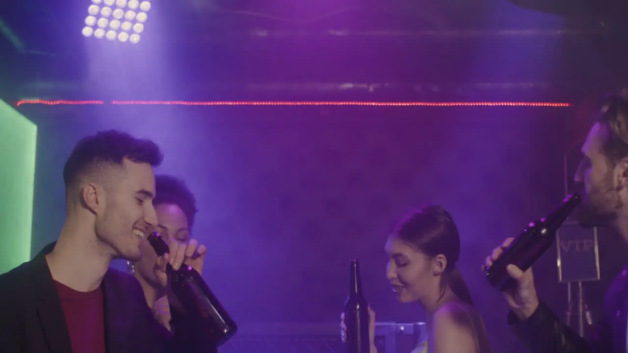 Group Of Four Young Friends Toasting With Beer Bottle While Dancing At Disco 2