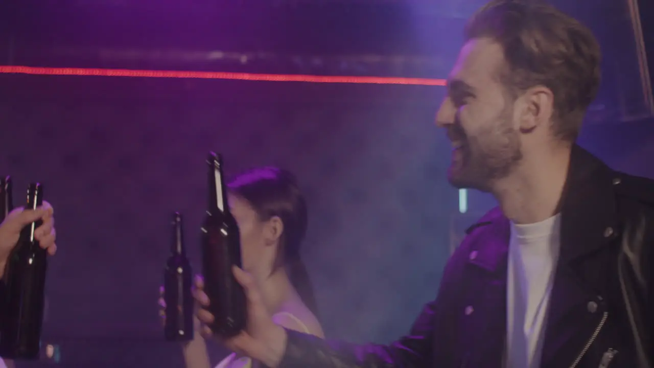 Group Of Four Young Friends Toasting With Beer Bottle While Dancing At Disco 1