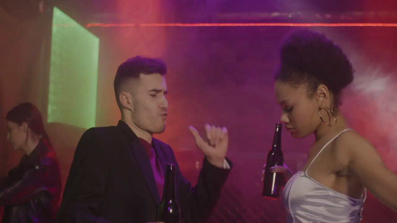 Happy Multiethnic Couple Drinking Beer And Dancing At Disco 2