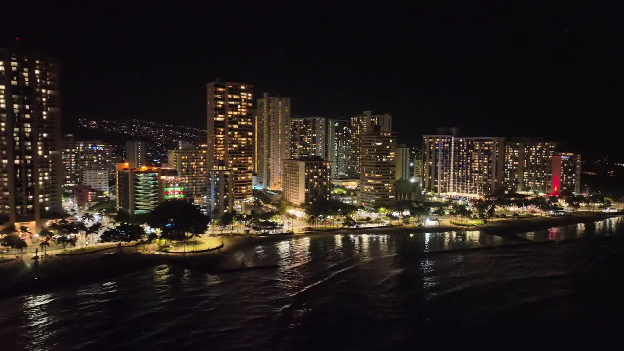 waikiki drone aerial footage at night with bright buildings and lots of light with traffic and palm trees oahu hawaii